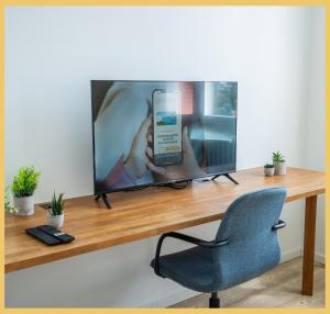 a television sitting on a wooden desk with a chair at Chez Gilles I Studio I Ambilly in Ambilly