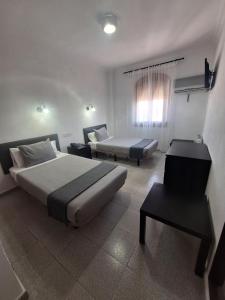 a bedroom with a bed and a couch and a table at Hotel Portugal in Lepe