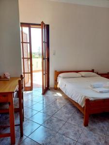 a bedroom with a bed and a table and a window at Genos suites in Stavros