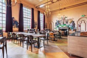 a dining room with tables and chairs and a fireplace at Stayokay Hostel Heemskerk - fully renovated April 2026 in Heemskerk