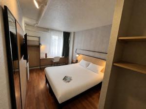 a hotel room with a white bed and a television at ibis Alençon in Alençon +30 photos