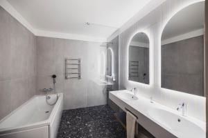 ein Badezimmer mit zwei Waschbecken, einer Badewanne und einem Spiegel in der Unterkunft Hotel Soho - Renovated 2026 in Tartu