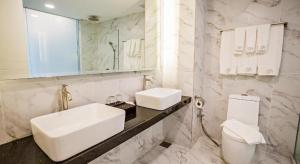 a white bathroom with a sink and a toilet at Grand Flora Hotel in Malacca