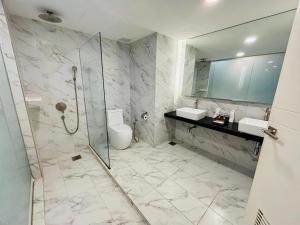 a bathroom with a shower and two sinks and a toilet at Grand Flora Hotel in Malacca