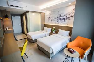 a hotel room with two beds and a chair at Grand Flora Hotel in Malacca