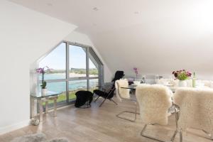 a dining room with a table and chairs with a view of the ocean at The Penthouse Fistral Beach, Newquay in Crantock