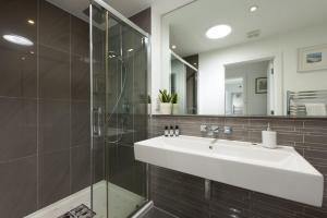 a bathroom with a sink and a glass shower at The Penthouse Fistral Beach, Newquay in Crantock +31 photos