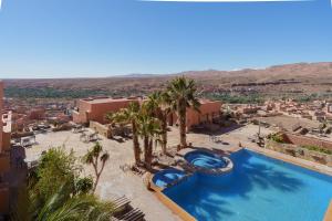 a pool with palm trees and a view of a city at Hotel Xaluca Dades in Boumalne Dades