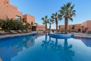 a large swimming pool with palm trees and buildings at Hotel Xaluca Dades in Boumalne Dades