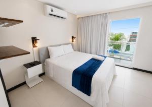 a white bedroom with a bed and a window at Pousada Oásis Tropical in Porto De Galinhas