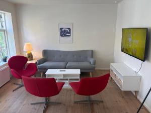 a living room with red chairs and a couch at Slotsgaarden ved Hesten in Randers