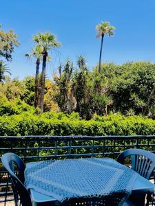 a blue table and chairs on a balcony with palm trees at Chambre du jardin in Rabat