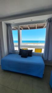 a blue couch in front of a window with the beach at Bahia creek in Las Grutas