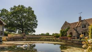 a swan swimming in a pond in front of a house at Grindstone Mill in Alderley