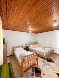 two beds in a room with a wooden ceiling at Lokthi Guesthaose in Theth