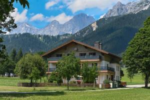 a house in a field with mountains in the background at Ferienwohnung Alpenecho in Ramsau am Dachstein