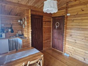 a kitchen in a log cabin with a sink and a door at CICHOsza in Lubkowo