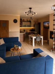 a living room with a blue couch and a kitchen at Pod skrzydłami in Miłomłyn