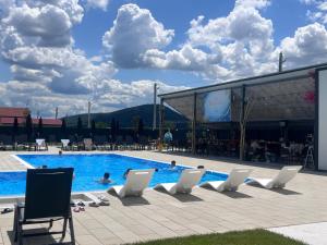 a swimming pool with white chairs and a swimming pool at La Chambre in Ineu
