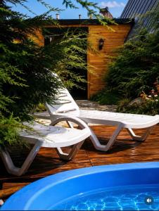 two white lounge chairs sitting next to a swimming pool at Altınkum Bungalov in Dereköy