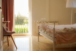a bedroom with a bed and a window and a chair at Willa pod Lipami in Bartoszyce
