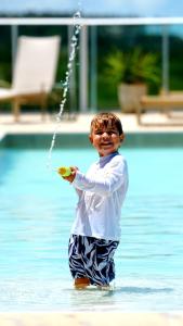 a young boy standing in the water holding a toy at Transamerica Dunas de Marapé - Alagoas in Jequia da Praia