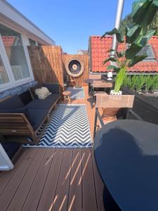 a deck with a couch and a table and a table at Van de Gruiterwonen in Axel