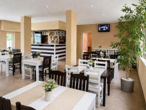 a restaurant with white tables and chairs and a tv on the wall at Hotel Alexander in Sofia