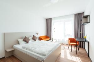 a white bedroom with a bed and a desk and chairs at Boardinghouse Air Tech Campus - smart Check-in in Weßling