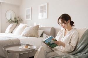 a woman sitting on a couch reading a book at Miroku Nagoya in Minami-sotoborichō