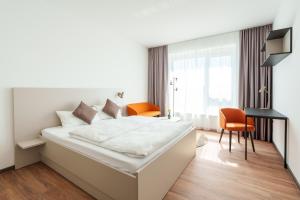 a white bedroom with a large white bed and chairs at Boardinghouse Air Tech Campus - smart Check-in in Weßling +66 photos