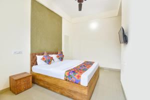 a bedroom with a bed and a tv on a wall at FabHotel Tiru Rooms in Pune