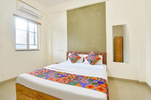 a bedroom with a bed with colorful sheets and a window at FabHotel Tiru Rooms in Pune