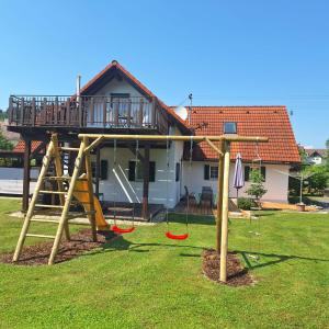 a house with a playground with swings in a yard at Ferienhaus Am Bach in Kirchberg an der Raab
