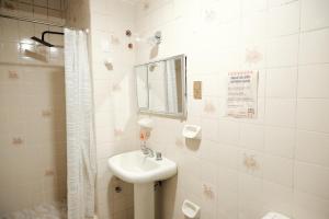 a white bathroom with a sink and a shower at Hotel Pata y Perro in Tarija