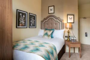 a bedroom with a bed and a table with a lamp at The Tudor House Hotel, Tewkesbury, Gloucestershire - The Coaching Inn Group in Tewkesbury