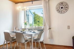 a dining room with a white table and chairs and a clock at Hesselberg-Oase Ferienhof Hüttner in Röckingen
