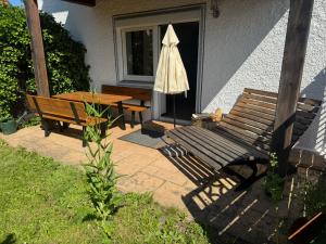 a patio with a table and a bench and an umbrella at Moderne große Wohnung mit Garten in Hausham