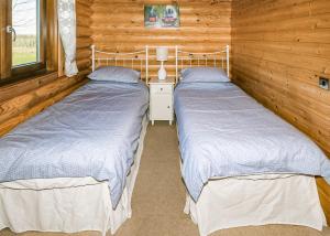 two beds in a room with wooden walls at Laxfield Lodges in Laxfield