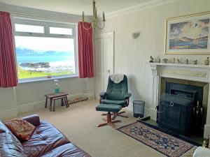a living room with a chair and a fireplace at South Bay Cottage in Saasaig