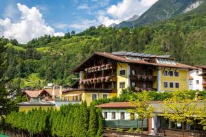 a yellow building on a hill with trees and mountains at Hotel Mozart in Landeck