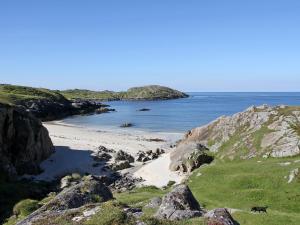 a beach with rocks and the ocean in the background at Myrtle Cottage - Uk5869 in Achmelvich