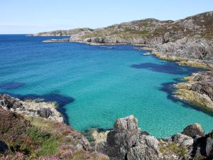 a large body of water with rocks and the ocean at Myrtle Cottage - Uk5869 in Achmelvich +8 photos
