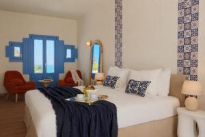 a bedroom with a white bed with blue accents at White Pearl Laokasti Suites in Oia