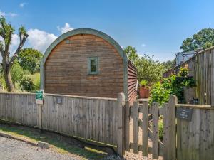 a wooden building behind a wooden fence at The Pod At Egmont in Newenden
