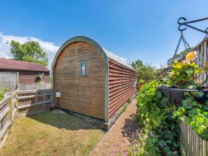 a wooden shed in a yard next to a fence at The Pod At Egmont in Newenden