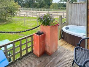 a deck with a tub and a planter with flowers at The Pod At Egmont in Newenden +10 photos