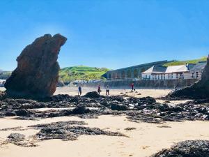 eine Gruppe von Menschen an einem Strand mit einem großen Felsen in der Unterkunft Jebel in Cullen
