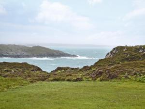 a grassy field with the ocean in the background at Thistle Cottage - Uk5867 in Achmelvich