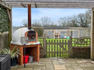 an outdoor brick oven in a yard with a fence at Egmont Farmhouse in Newenden